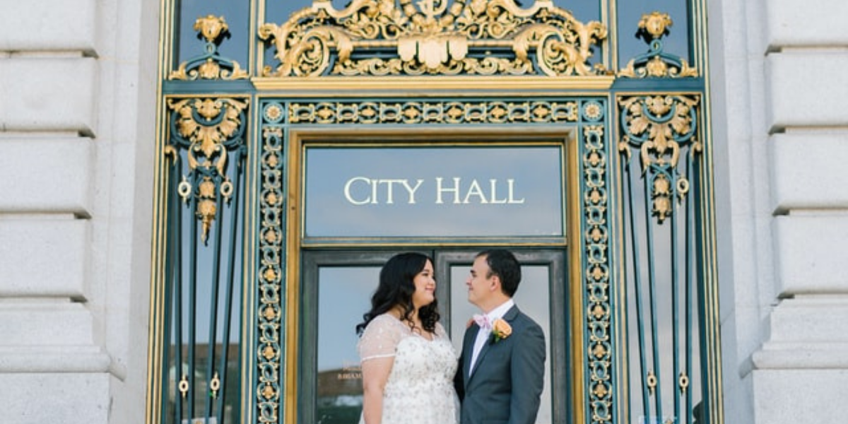 bride and groom posing in front of city hall on wedding day