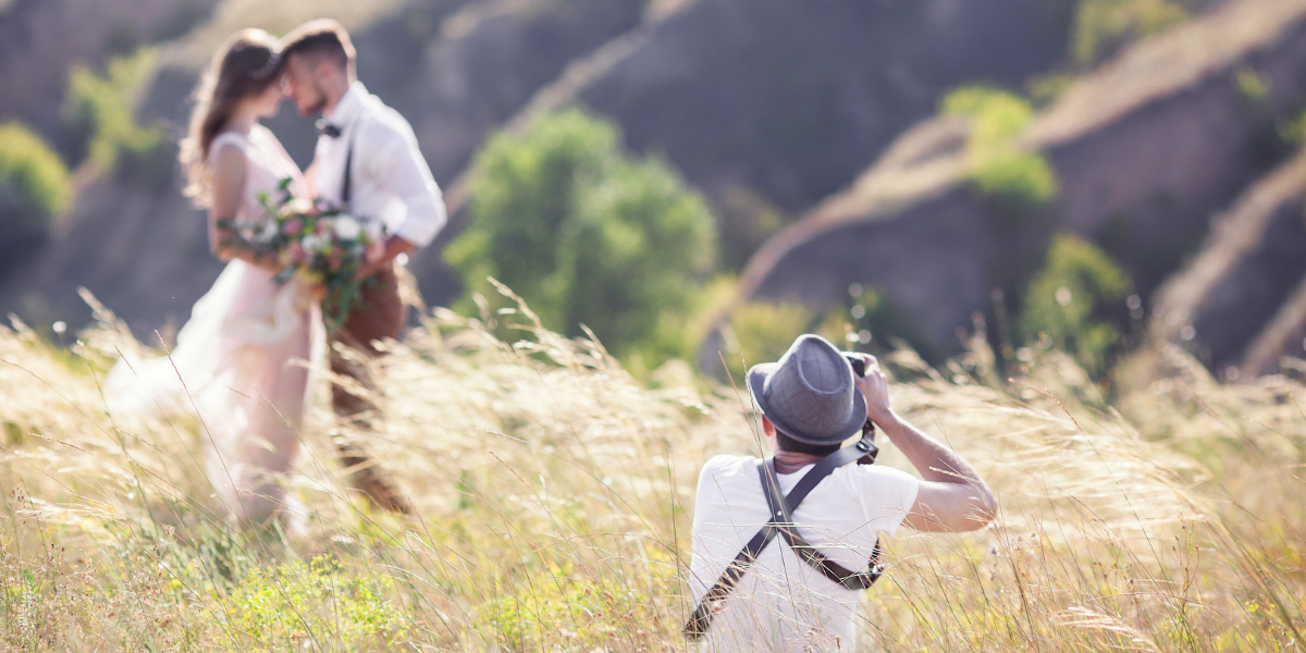 wedding photographer shooting couple in field