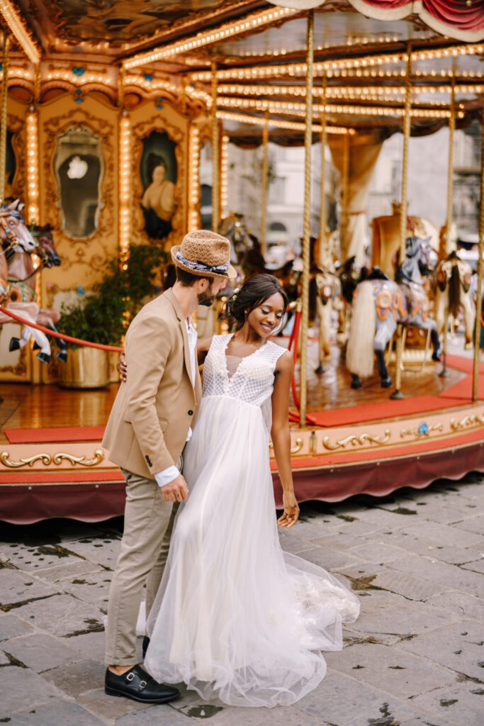 African American bride and white groom in front of carousel