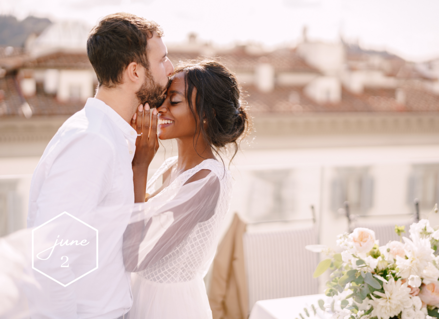 Groom kisses bride on forehead at rooftop wedding reception in Florence Italy