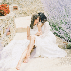 Two brides in wedding dresses embracing in lavender