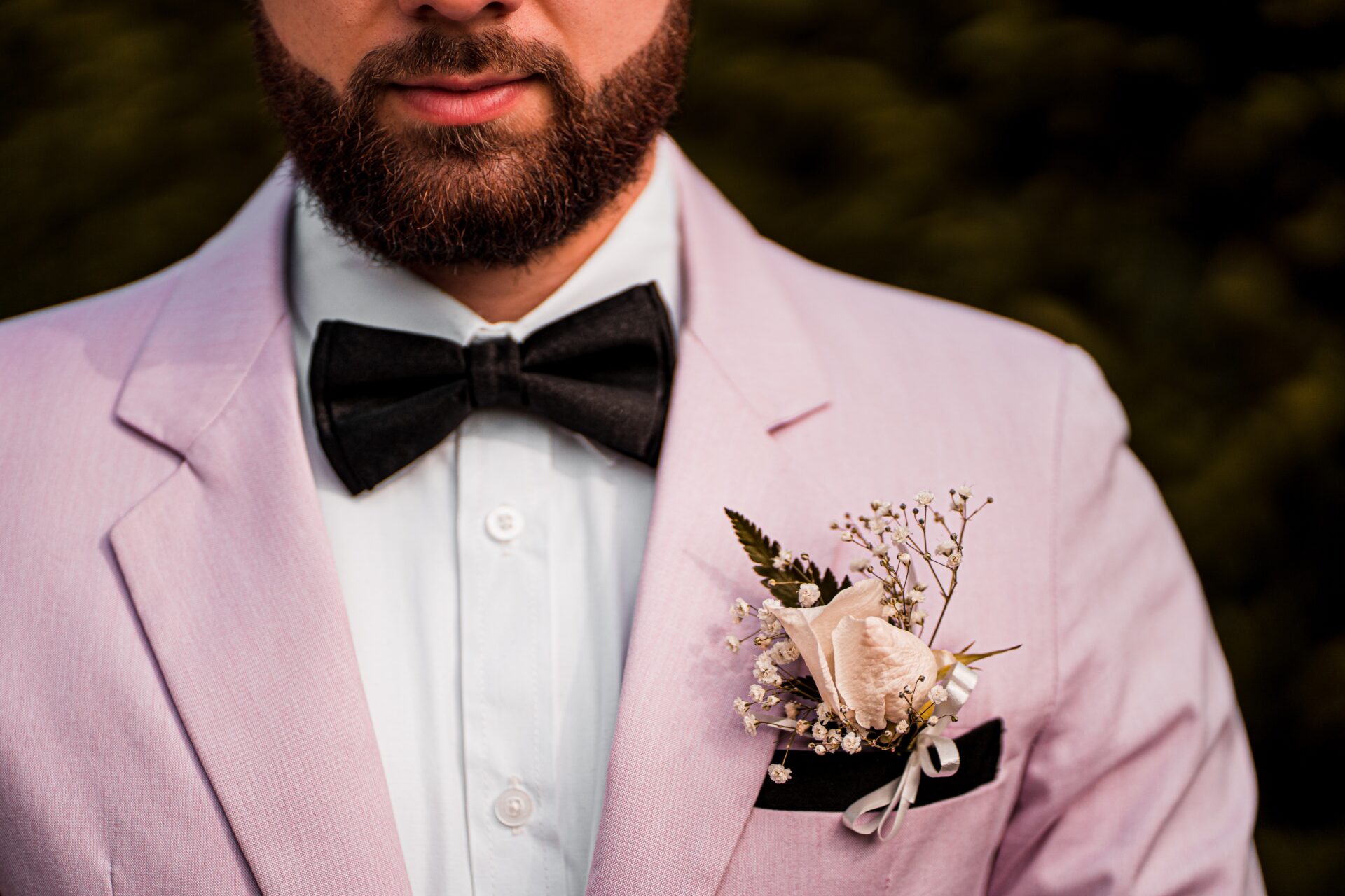 Groom wearing pink suit with black bow tie