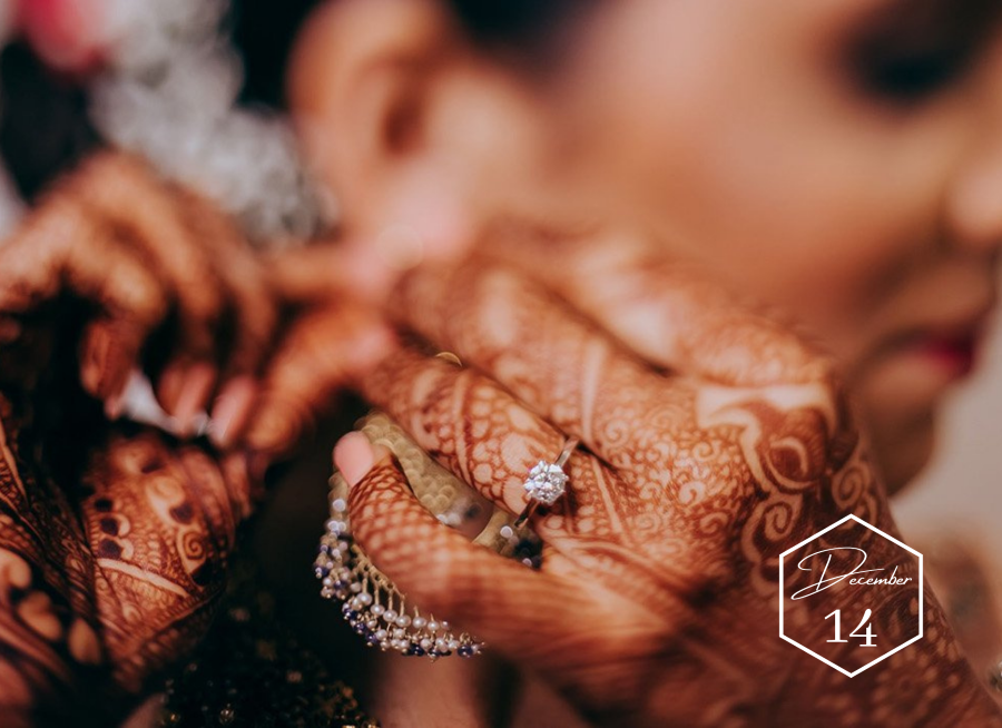 beautiful bride with henna tattoos on hands putting on earrings