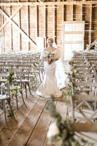 Beautiful bride walking down aisle in rustic barn