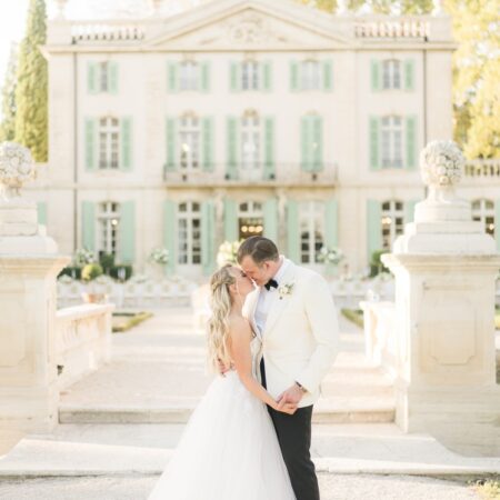 bride and groom posing in front of European mansion