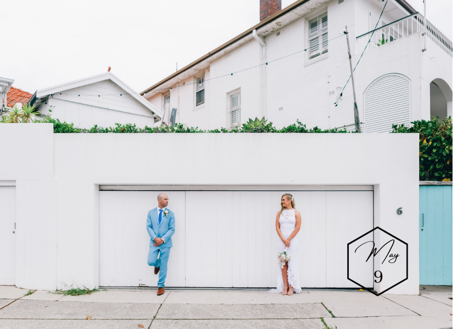 Bride and groom pose for portrait outside garage at home wedding