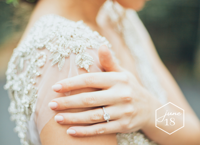 Bride wearing vintage beaded wedding dress shows engagement ring