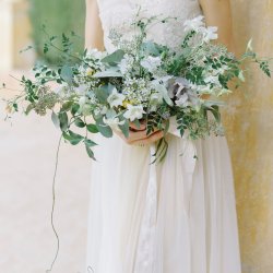 Bride in ivory dress holding beautiful bouquet at Fine art wedding